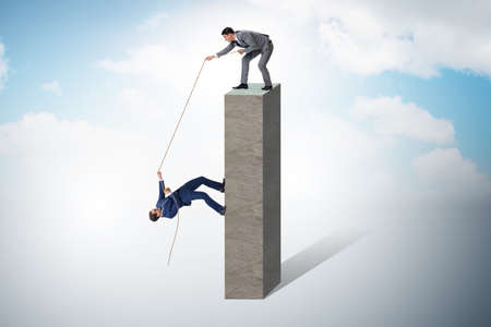 Businessman helping colleague with ropeの写真素材