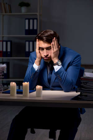 Businessman working late in office with candle lightの写真素材