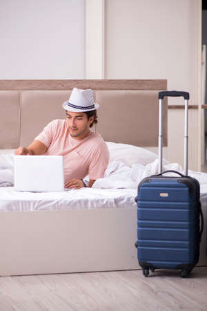 Man with suitcase in bedroom waiting for tripの写真素材