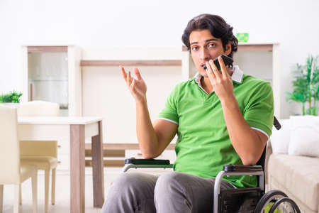 Young handsome man in wheelchair at homeの写真素材