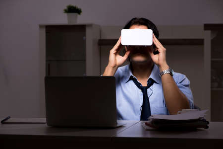 Young employee with virtual glasses at night in the office