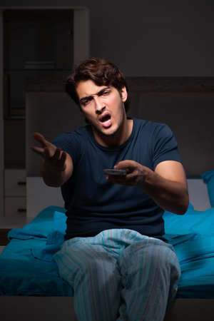 Man watching tv at night in bedの写真素材