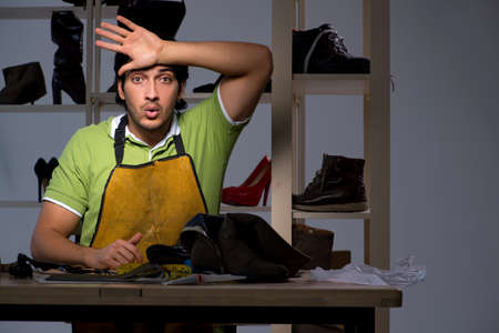 Young shoemaker in workshop at night