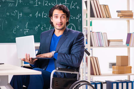 Young handsome man in wheelchair in front of chalkboardの写真素材
