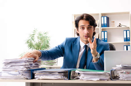 Young handsome busy employee sitting in officeの写真素材