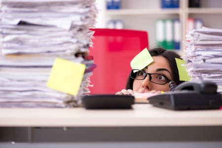 Young female employee in conflicting priorities conceptの写真素材
