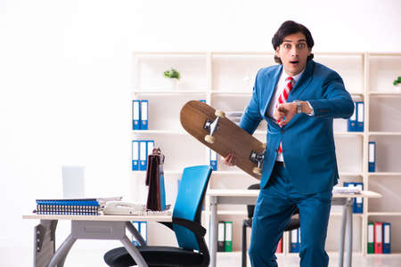 Young handsome businessman with longboard in the officeの写真素材