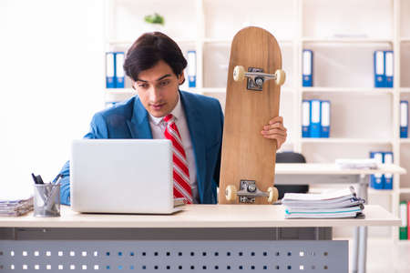 Young handsome businessman with longboard in the officeの写真素材