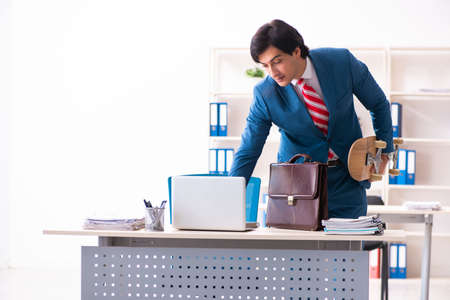 Young handsome businessman with longboard in the officeの写真素材