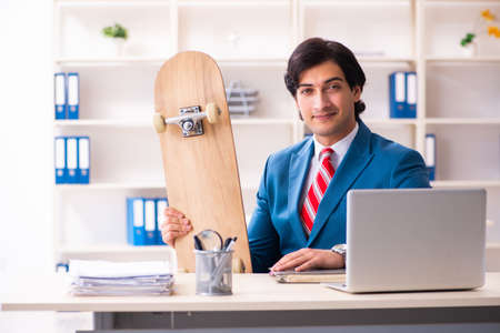 Young handsome businessman with longboard in the officeの写真素材