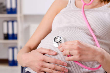 Young pregnant employee working in the officeの写真素材