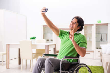 Young handsome man in wheelchair at homeの写真素材