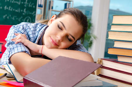Female student with many books sitting in the classroomの写真素材