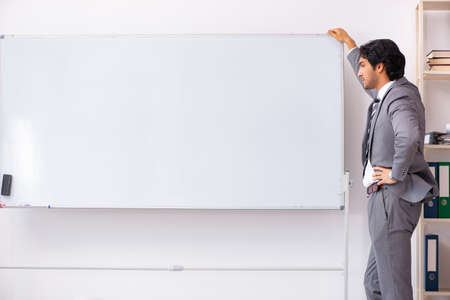 Young handsome businessman standing in front of whiteboardの写真素材