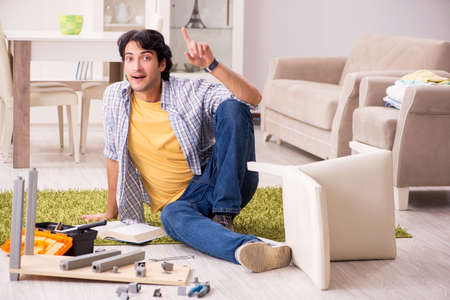 Young handsome man repairing chair at homeの写真素材