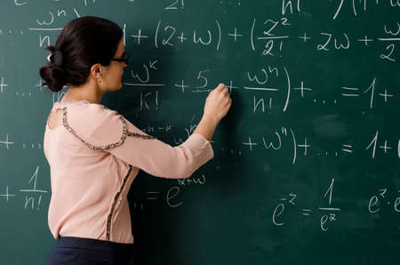 Female teacher standing in front of chalkboardの写真素材