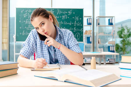 Young female student taking the exam in classroom