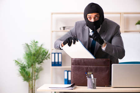 Male gangster stealing information from the officeの写真素材