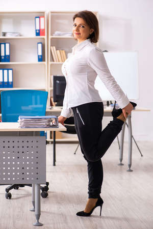 Middle-aged female employee doing exercises in the officeの写真素材