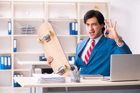 Young handsome businessman with longboard in the officeの写真素材