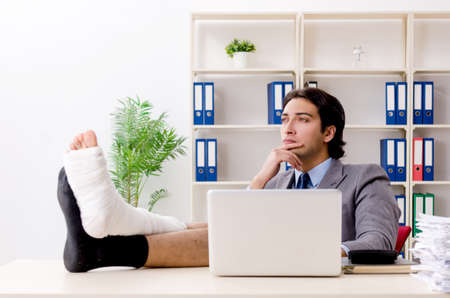 Leg injured employee working in the officeの写真素材