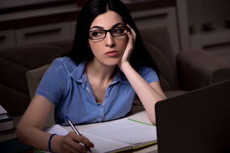 Young female student preparing for exams at night time