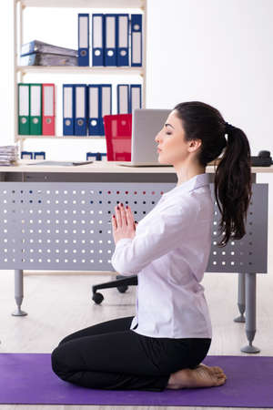 Young female employee doing exercises in the officeの写真素材