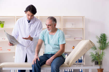 Old man visiting young male doctorの写真素材