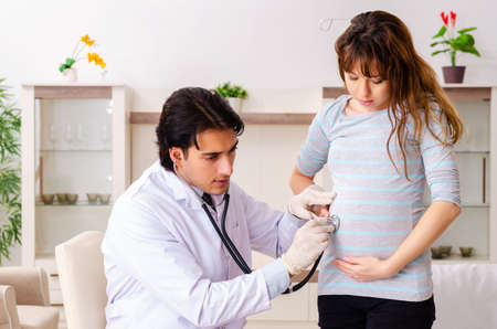 Young handsome doctor visiting pregnant woman at homeの写真素材