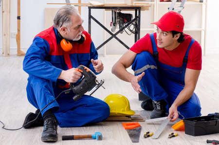 Two professional contractors laying flooring at homeの写真素材