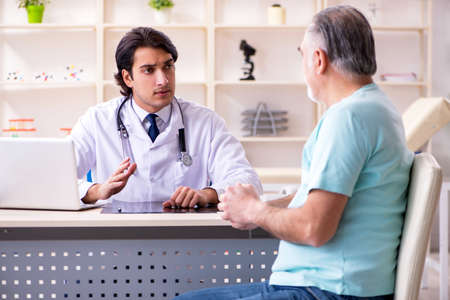 Old man visiting young male doctorの写真素材