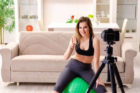 Young beautiful girl blogger doing exercises at homeの写真素材
