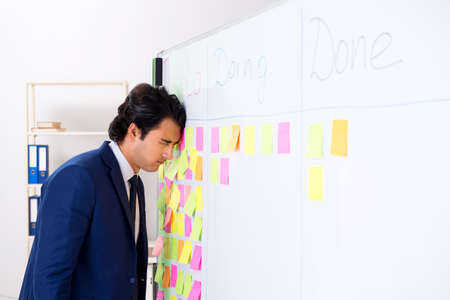 Young handsome employee in front of whiteboard with to-do list