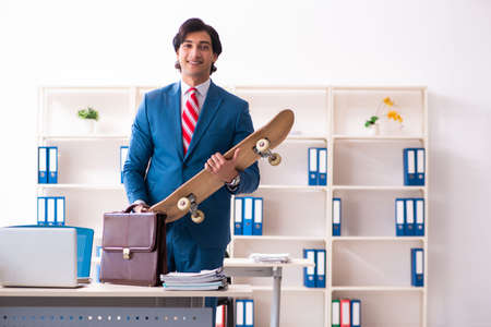 Young handsome businessman with longboard in the officeの写真素材