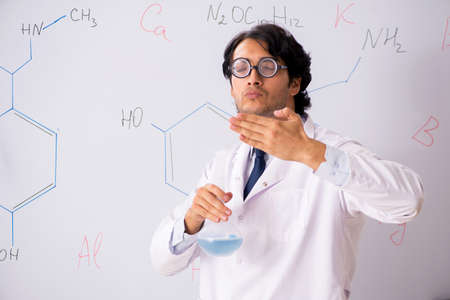 Young funny chemist in front of white board
