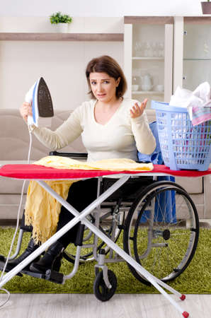 Woman in wheelchair ironing at homeの写真素材