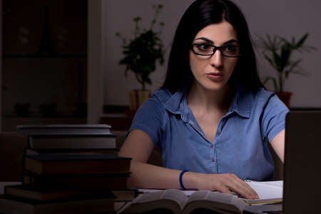 Young female student preparing for exams at night time