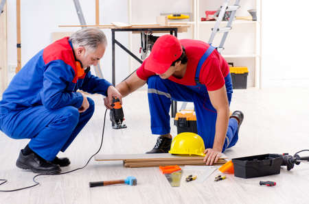 Two professional contractors laying flooring at home