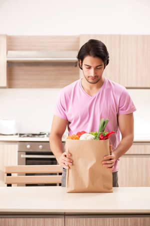 Young handsome man with vegetables in the kitchenの写真素材