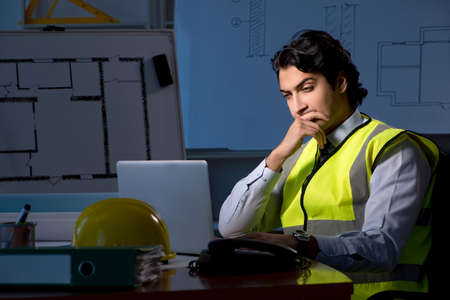 Young construction architect working on project at night