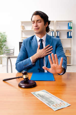 Young handsome judge sitting in courtroom