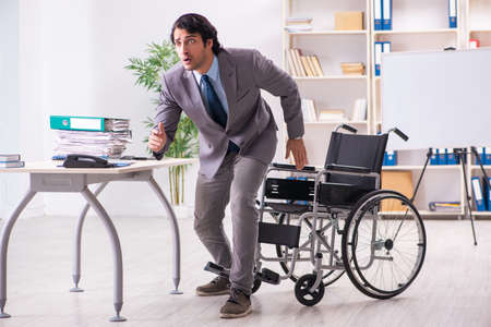 Young handsome employee in wheelchair at the officeの写真素材