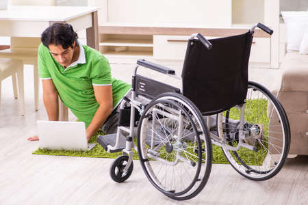 Young handsome man in wheelchair at home
