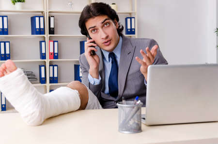 Leg injured employee working in the officeの写真素材