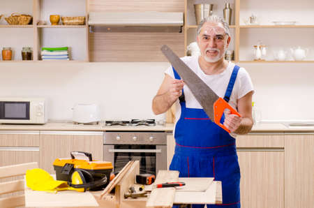 Aged contractor repairman working in the kitchenの写真素材