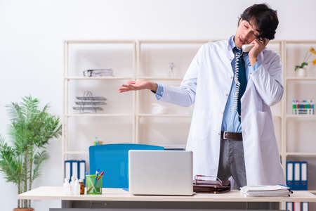 Young male doctor drinking in the officeの写真素材