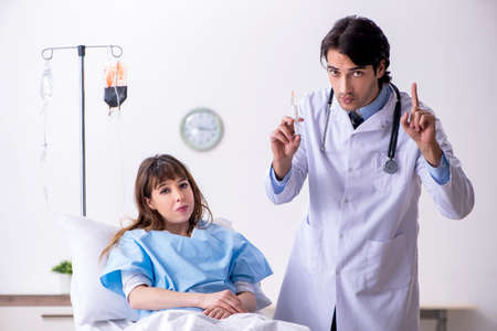 Male doctor visiting female patient in ward