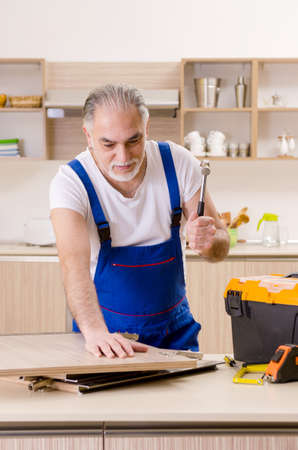 Aged contractor repairman working in the kitchenの写真素材