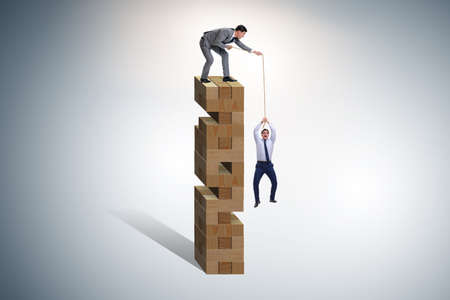 Businessman helping colleague with ropeの写真素材