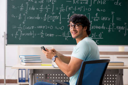Young male student mathematician in front of chalkboard